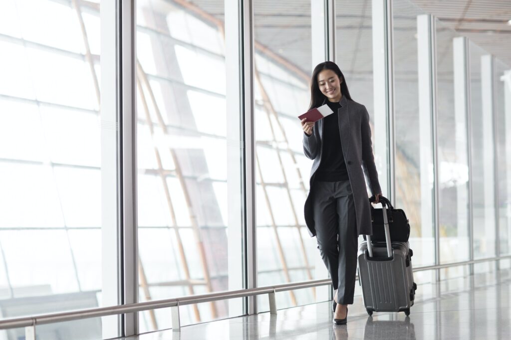 Businesswoman pulling wheeled luggage in airport lobby
